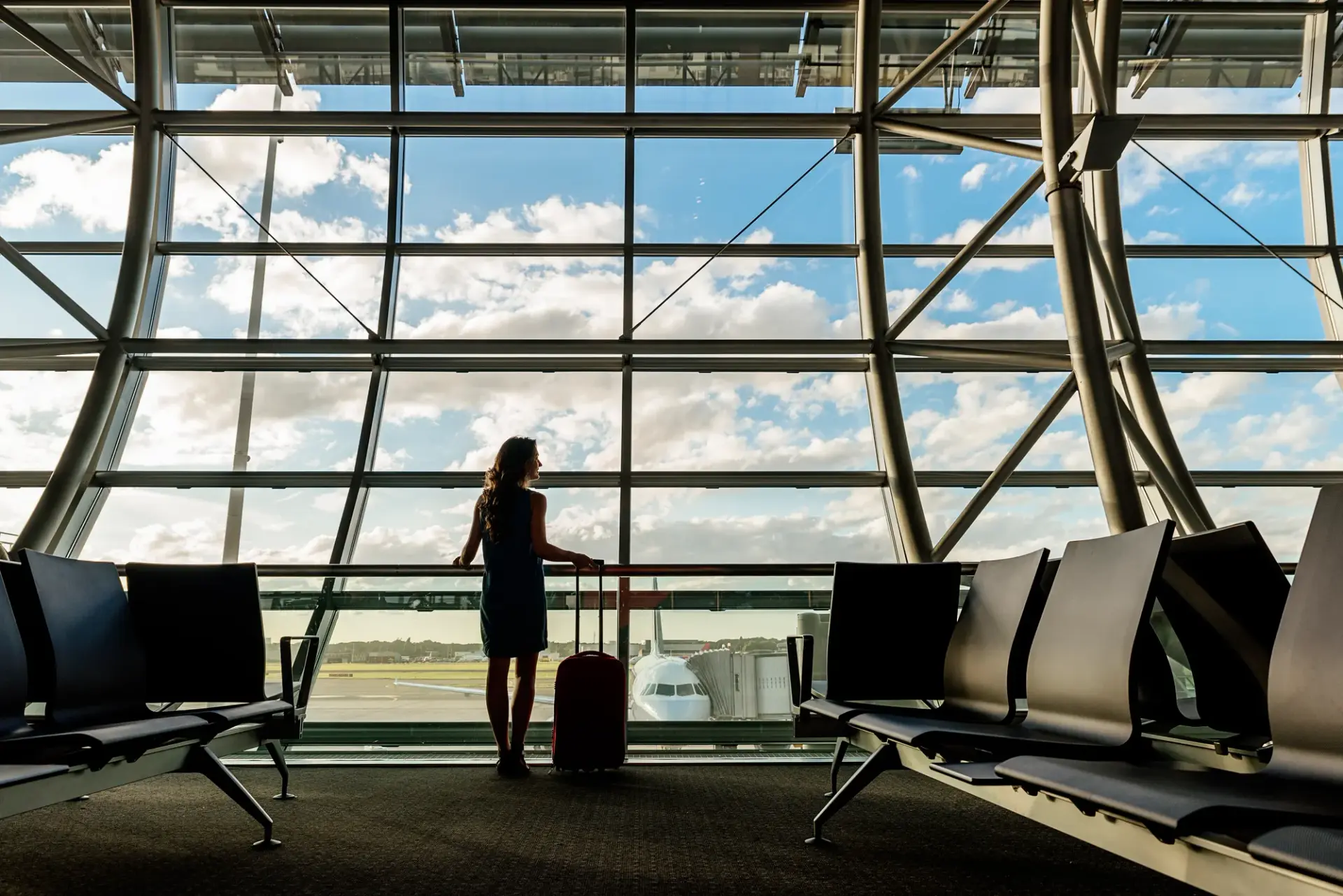 Voyageuse avec sa valise devant un avion dans un terminal d'aéroport